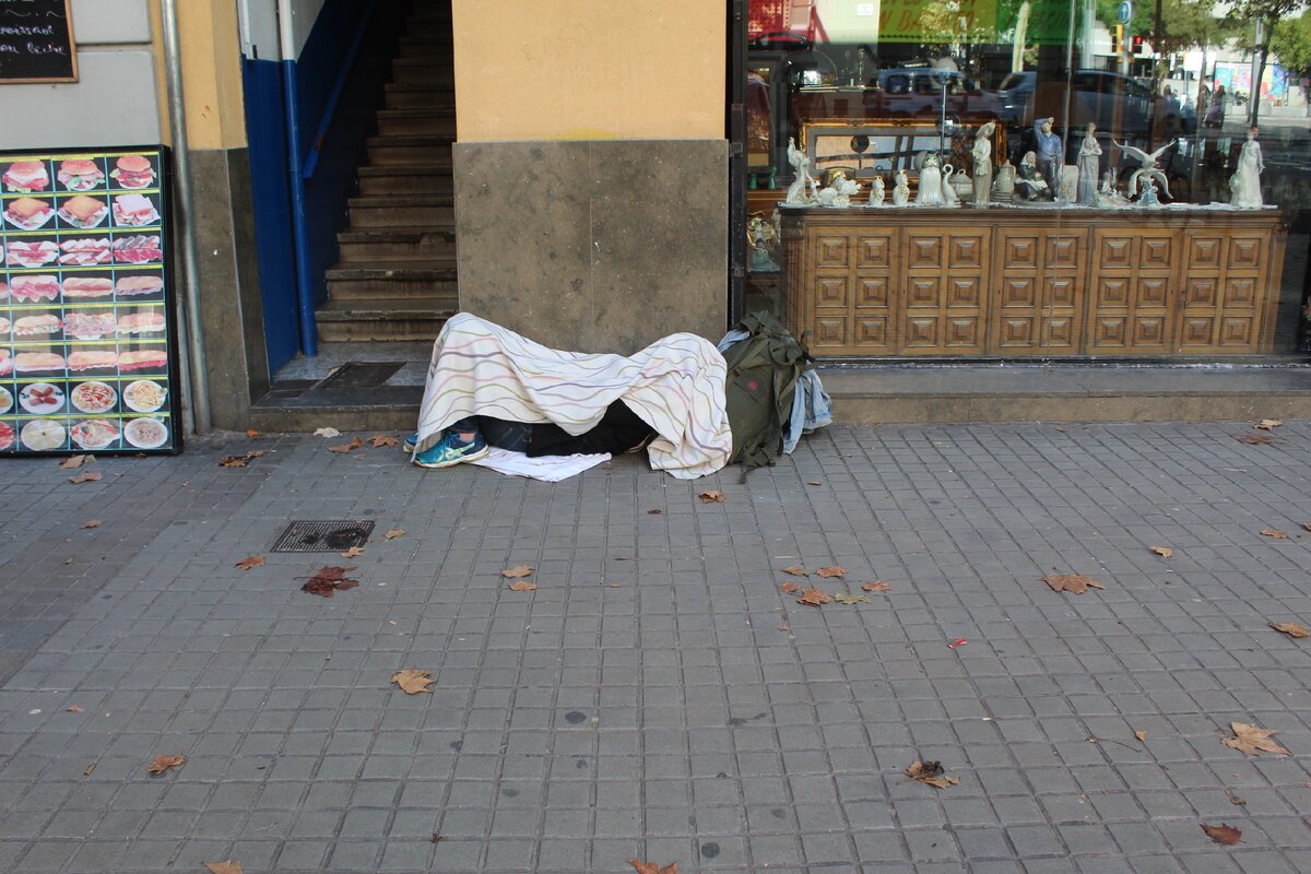 Бездомный, спящий у одного из подъездов барселонского дома