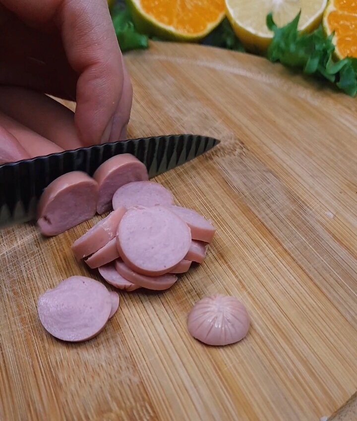 Затем сосиски, лучше конечно взять немного подкопченые (они улучшат вкус блюда). Нарезаем на средние кусочки