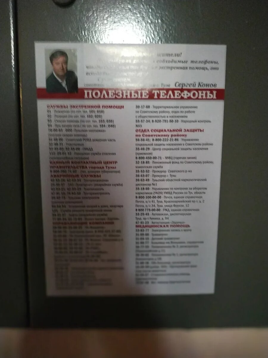 "Информационный листок" с "полезными телефонами" с фотографией Сергея Конова на , распределительном щите в подъезде дома по Лейтейзена 9