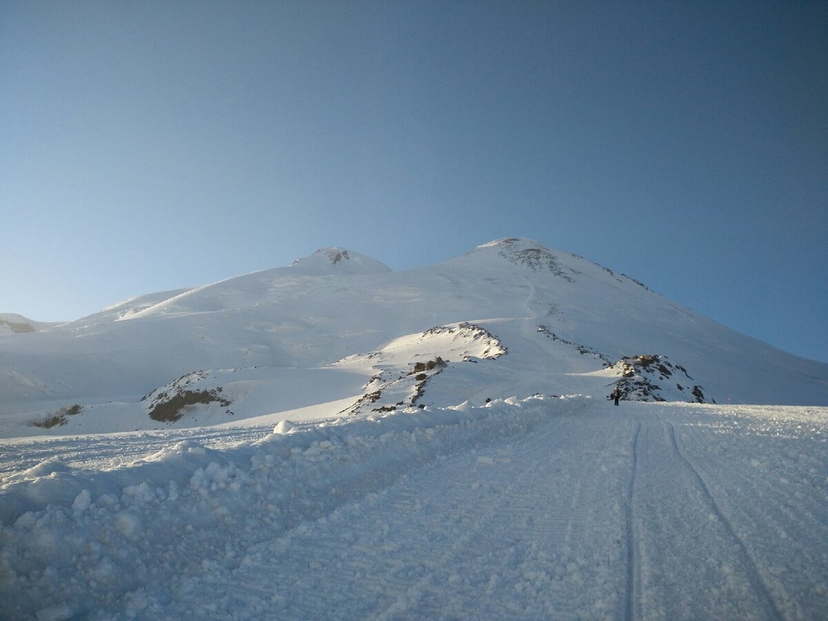 След от ратрака на склоне Эльбруса. Вершины кажутся близкими, но это зрительный обман)