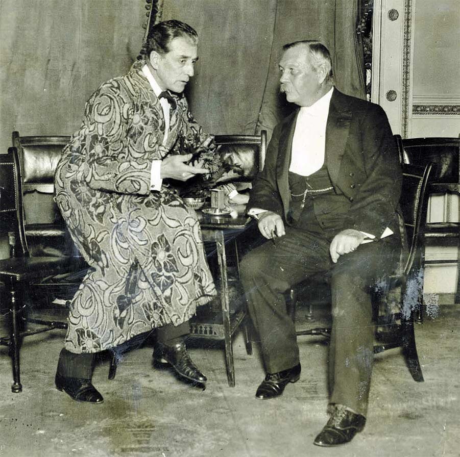 На фото: сэр Артур Конан Дойл на ежегодном ужине компании «Столл» 27 сентября 1921 года беседует с актёром Эйлом Норвудом, игравшим Шерлока Холмса. 
