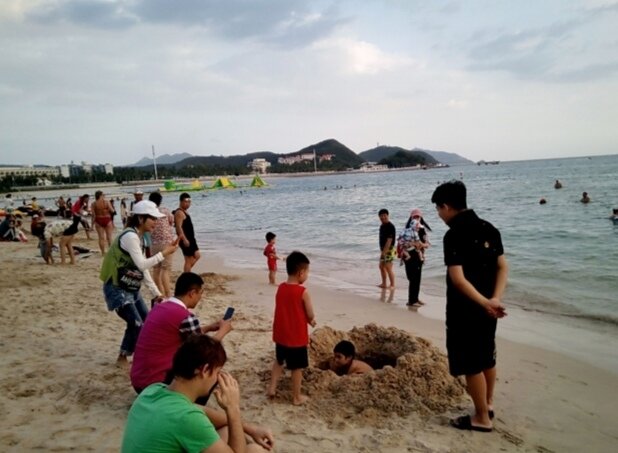 Саша копает яму на пляже Дадунхай,  а китайцы фотографируют Сашу и говорят с ним на китайском языке. Личное фото. 