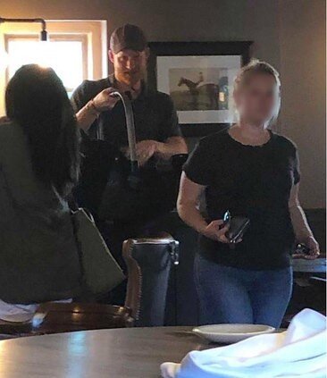 Гарри держит в руках автомобильную переноску, в которой спит малыш Арчи. Рядом Меган, собирает остальные вещи