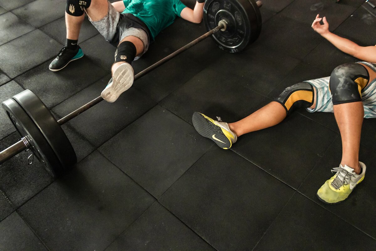 https://www.pexels.com/photo/two-men-lying-on-gym-floor-beside-black-barbell-2261483/