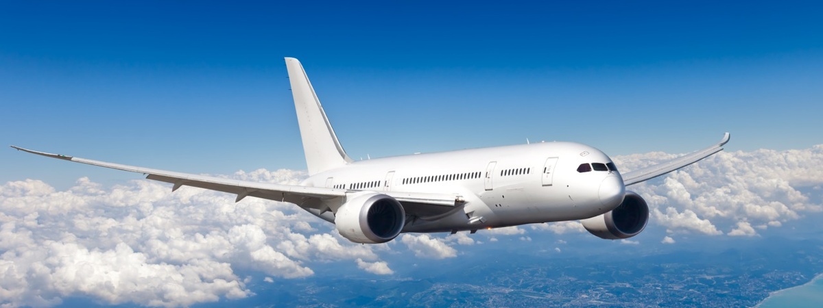 Boeing 787-8 BBJ летит в голубом облачном небе над морем.