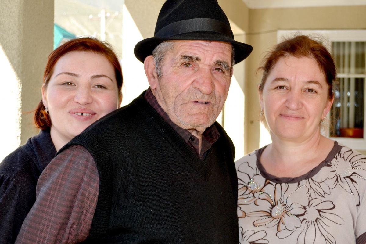 Каплан с дочками Мариам и Хаулат

Во времена нашего далёкого детства наша мама говорила: «Все мои дети получат образование». Отец недоверчиво комментировал: «Наполеоновские планы…»
Мама тоже была выселена, когда ей было от роду только год, и отца, без вести пропавшего на войне, не помнила. Но все тринадцать лет на чужбине рядом с ней была мать. Она была рядом всегда, помогала ей растить восьмерых детей. Это был мир, где была защита и можно было мечтать. И она мечтала! Так свободно, так легко, так смело… Так никогда не смел мечтать отец. Он боялся мира. Не доверял ни миру, ни судьбе. Ещё в 1942 году сводный отряд НКВД, отступая, сжёг его село Сауту, расстреливал стариков, детей, женщин. Он убегал от солдат, пятилетний ребёнок. Он стоял у запертой двери, за которой слышались голоса. Стучал – не открывали. Люди с оружием приближались. Постучался ещё.
- Откройте! Иначе я скажу им, что вы здесь.
Ему открыли. Он никогда не вспоминал эти дни. Лишь однажды, для телевизионной передачи, уговорили рассказать о трагедии его родного села. Тяжело говорил, дыхание прерывалось. Ужасы прошлого снова становились явью. После ухода отряда НКВД из Сауту, люди бежали в горы. Они боялись, что убийцы вернутся. Страх сводил с ума. Горы утешали, горы возвращали силы. Может, побег в горы был не столько желанием укрыться от отряда НКВД, сколько поиском покоя для душ, охваченных ужасом. Горы помогли. Через три дня наступила тишина. И люди вернулись в село.
Сожжённых узнавали по фрагментам одежды. Хоронили всех в общей могиле.
Отец не умел мечтать. Потому что в его мире он ничего не решал, всё рушилось по воле других сил. В Кызыл-Кая, на чужбине, заболела мать: щитовидная железа. Решили оперировать. Хирург на ней показывал студентам-практикантам, как надо оперировать. Один из них решился повторить движение, но уже не в воздухе, а на больной и нечаянно зарезал её. Нет, никого за это убийство не осудили, это ведь была всего лишь жизнь спецпереселенки. Восемь сирот в семье... пришлось бросить школу. Пытался подрабатывать. На шахте оторвало пальцы. Вспоминал, что еврей, зашивший ему руку, сидел на ступенях, курил и… умер.
Отец читал по слогам. Выписывал газету на балкарском языке «Заман»: в каждом номере искал мою фамилию. Если не находил, беспокоился, думал, что я заболела. А я просто ленилась, мало писала. Но однажды прочитал один мой материал: по слогам. Это было интервью с помощником Духовного управления мусульман Кабардино-Балкарии Хызыром Отаровым. Он говорил о Боге и вере.
- Это же длинное интервью, как ты одолел?
- Целый день сидел.
- Мама же могла тебе прочитать. Почему не попросил?
- Сам прочитал.
У мамы было среднее образование, она бегло читала, знала наизусть много стихов Пушкина, Лермонтова, Абая. И каждый день читала балкарского поэта Кязима Мечиева. И она знала: образование – доступный мир, стоит только захотеть ступить в него. Для отца это был удивительный и закрытый мир, мир для избранных счастливцев.
Отец в больнице. В большом термосе суп с тефтелями, на базаре купила фрукты и несколько пачек «Примы». Застала его в коридоре.
- Здравствуй. Покушаешь, пока всё не остыло?
- А сигареты купила?
- Да.
- Какие?
- Как какие? Какие ты куришь – «Приму».
- Надо было другие. С фильтром. Я уже сказал в палате, что все мои дети образованные, а тут… «Прима».
- Ты не знаешь, что сейчас все с высшим образованием? Чем тут хвастаться? Чем гордиться?
- А чем ещё?..
Если бы он учился, мог бы быть писателем. Знал сотни сказок. Что сочинил сам? Что слышал? Теперь уже и не сказать. Утеряны навсегда.
Когда собирались на сенокос в горы бригадами, каждая просила его присоединиться к ним. Потому что вечера в горных кошарах были особенными с его сказками. Порою одну сказку он рассказывал несколько вечеров. В записанных мною двух-трёх сказках явственно слышна его исповедь. В одной из них один из персонажей убивает каждого гостя, который спрашивает про огромную чёрную собаку: почему она лежит на почётном месте? Эта собака – его отец. Сказочные превращения – обычное дело. Но вот интересная деталь: гостю, который был столь интуитивно-деликатен, что ничего не спросил, этот человек советует: «Не спрашивай о тайне человека, не допытывайся, в чём его боль. И боль, и тайна есть у каждого, но они его, и только его». В другой сказке «Три совета» старец даёт юноше совет создать семью с девушкой из своего села и своего сословия. Нет, мой отец вряд ли думал о безусловных трудностях межнациональных браков, просто внешний мир именно к нему много раз был агрессивно - враждебен.
…Женился брат, родился первенец. Мы, сёстры и отец, поехали в дом снохи. У меня ночью была бессонница и казалось, что голова сейчас расколется на куски. А отец за праздничным столом рассказывал сказку. От головной боли я ничего не понимала, его громкий голос усиливал боль. Но когда я смогла поднять голову и посмотреть на него, увидела человека в другой реальности. Речь лилась как горная река: бурно, напористо, неостановимо. Глаза внимательно следили за невидимым действием. Позже я часто вспоминала те минуты и поняла: отец продолжал убегать от отряда НКВД, он бежал в сказку. «Не спрашивай о тайне человека, не допытывайся, в чём его боль», - говорит один герой в его сказке.
Что было болью отца? Сауту, его расстрелянное, сожжённое село. Где женщина, ушедшая проведать родителей в соседнее село, вернулась и застала трупы шестерых своих детей во дворе. Она сошла с ума. И её тоже выселили потом в Азию. Отец не рассказывал про Сауту. Но когда дали там участочек земли, со рвением стал расчищать её, чтобы посадить сад. Он был садовником. И дом хотел построить, но не было уже ни сил, ни здоровья: старость… А когда был моложе, в колхозе не нашлось для него кусочка земли.
Когда умер его отец, ему в наследство достался склон горы. Не земля, а каменный склон горы. Но он там, на камнях, сумел взрастить чудесный яблоневый сад. И сейчас осенью его могила бывает усыпана яблоками, над могилой раскинула свои ветви старая яблоня: такая неслучайная счастливая случайность.
Его болью было и раннее сиротство. Любая передача, художественный или документальный фильм про сирот вызывали не мужскую скупую слезу, а плач.
Люди, выжившие в расстрелянных отрядом НКВД селениях Сауту и Глашево, жили потом со страхом всю жизнь. Записывала исповеди многих из них и видела в глазах страх. Зайнаф Глашева сказала: «Столько лет прошло с 1942 года, это прошлый век, а остаюсь одна и всё оживает. На Новый год дети взрывают бомбочки во дворе, а у меня начинает стучать сердце, выхожу и прошу: «Не взрывайте! Я боюсь!»
И отца преследовал страх. Когда мама купила мебель для зала, он возмущался. Он хотел, чтоб были неприкосновенные сбережения. На чёрный день. Он знал: чёрные дни наступают неожиданно.
Пережитые чёрные дни обострили его чувства, он без слов понимал людей. Когда пастух с нашей улицы не вернулся домой, вечером сельчане пошли в горы его искать. Но быстро темнело и люди вернулись обратно. А отец ещё с одним человеком пошли дальше и нашли труп. Отец знал: близким будет невыносимо тяжело пережить ночь в неведении. Определённость уже облегчение.
На свадьбах и похоронах своего рода он был главным организатором. Сердце, чью защитную оболочку растворили страдания, оголённое, беззащитное сердце сироты было полно желанием помогать людям.
