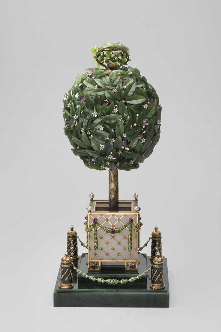 Пасхальное яйцо "Лавровое дерево". Это пасхальное яйцо было изготовлено Фаберже в 1911 году для царя Николая II, который преподнёс его в подарок своей матери. Мы видим, что подставка, колонны, декорированные золотом и листья выполнены из нефрита.