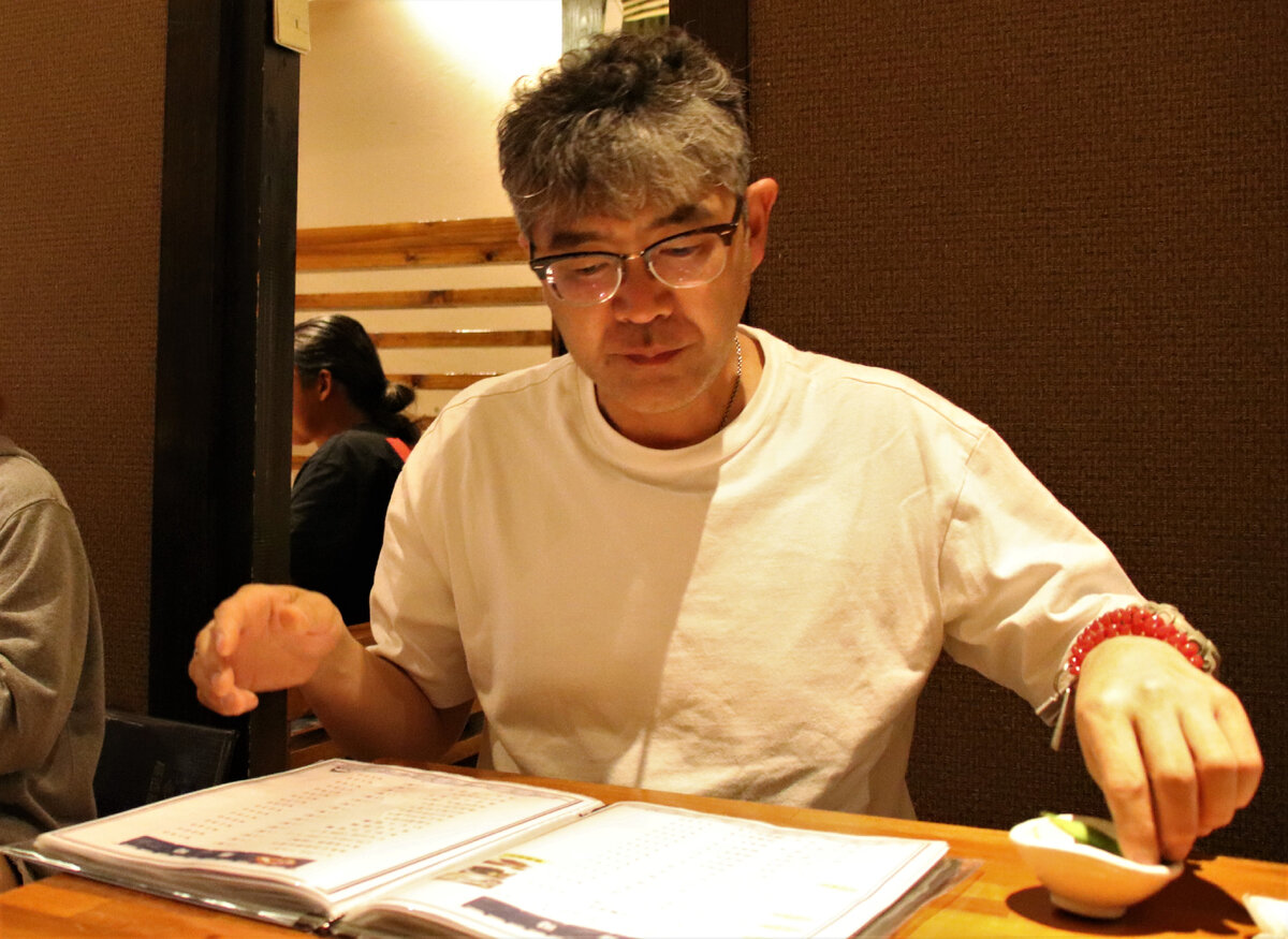 Таро изучает меню и ест эда-мамэ (традиционная закуска к пиву в Японии)