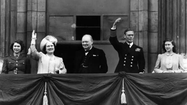 Британский премьер-министр Уинстон Черчилль и британская королевская семья машут с балкона Букингемского дворца во время празднования Дня Победы в Лондоне. Фото: Reg Speller / Getty Images