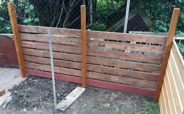 Задняя стенка компостника. Металлическая труба на переднем плане нужна для поддержки серединной стенки при установке. Фото автора