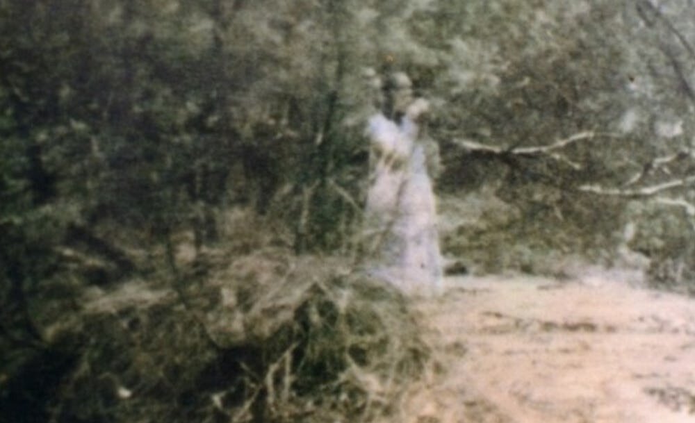 Случилось это со мной лично в 2001году! Есть у нас в районе маленькая речушка Коща.  Так вот мы с братом с конца июля до осени ездили на неё за раками. Обычно раков ловят ночью, кто ловил тот знает что это такое и как. А на Коще ловятся только днём в пасмурную погоду, а ещё лучше когда дождь моросит! Так вот конец июля пять часов утра моросит дождь мы созваниваемся и едем на Кощу. (На мотоцикле ИЖ Планета 4). Приехали на речку  расставил раколовки, посидели перекурили и пошли проверять их. Прошли проверили и вернулись на исходное место, сидим перекуриваем, разговариваем о разном. Смотрю из берега торчит то-ли ветка, то-ли кость.  Спустился посмотреть поближе оказалась кость. Видно весной размыло во время половодья . Переглянулись и решили раскрасить, чтобы посмотреть что там или кто. Выкопали бойца нашего, убит был в голову (пулю вытащили из черепа)при нём ничего не было только что пуговицы наши по ним и поняли кто перед нами. Бои в тех местах были страшные, там по серёд поля даже стелла стоит бойцам красной армии,(правда народ про неё уже не помнит а многие и вовсе не знают!) Так вот выкопали посмотрели и на прежнее место закопали и ловим дальше даже не вспоминаем об этом. Время к вечеру, девять начало десятого часа. Собираемся и едем домой, путь не ближний до ближайшего села 8км. Проехали мы 2км, на встречу нам идёт девушка. С дальнего расстояния выглядит молодо, я ещё брату сказал мол сейчас тормозну познакомимся. Кошмар был когда подъехали почти в плотную, вот её описание, сразу напомню был конец июля! Волосы распущенные длинные, русые с проседью. Одета, чёрный плюшевый шушун(полушубок),такой ещё у моей покойной пробабки был, юбка синяя длинная по земле подол тащится и по низу расшита лентами (как на картинах). С плеча свисает шаль синяя в крупную черную клетку (такие раньше в кино показывали часто про сельскую жизнь) и по земле тянется. Лицо было как у анкологического больного (простите за сравнение) череп обтянут кожей, кожа жёлто-воскового цвета, глазницы проваленные чёрные. Идёт  так как будто не идёт а по воздуху плывёт(не видно шевеления ног под юбкой). Когда я пролитал мимо неё она просто остановилась и проводила нас взглядом пока мы не скрылись за деревьями. Брата ещё долго трясло после этой встречи,  да и меня самого до сих пор потрясывает когда я эту историю рассказываю своим детям. Вывод моего брата что это мать этого бойца искала успокоится не могла, а мы мол потревожил и её и сына!   Так что это могло быть по вашему  если это не мистика то что??? Если это просто больная раком женщина так что она там делала в десятом часу вечера!? С того места где мы её встретили до ближайшего села в одну сторону километров пять_шесть в другую побольше будет. С левой стороны от дороги осиное болото, а с правой река Жиздра и по близости не одного населенного пункта. Если скажете что глюки, то массовых галюцинаций не бывает. Был трезвый на тот момент не пил вообще около года! А брат до армии не выпивал даже по большому поводу.  Так что давайте без подколов, это реальная история приключившаяся со мной и моим братом! Если кому есть что сказать по делу пишите в комментариях буду рад вам ответить и по обсуждать! Подписывайтесь ставьте пальчики в верх! У меня ещё есть подобные истории правда не мои личные но от прямых участников историй (не списанные от куда нибудь)!