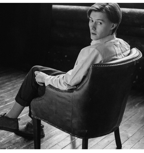 Миша Кострецов изящно сидит в кресле