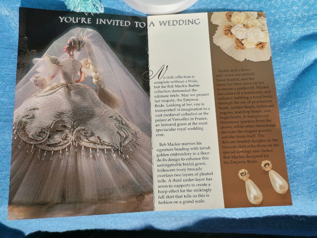 «Ни одна коллекция может быть полной без невесты, но коллекция от Боба Маки требует нечто непревзойденное! Позвольте Вам представить Ее Высочество Императрицу-Невесту. Стоит только взглянуть на нее, как Ваше воображение перенесет вас в просторный средневековый собор или во французский Версаль, как гостя на самой зрелищной королевской свадьбе, какую когда-либо видел мир!
Боб Маки вложил в наряд свой характерный подчерк, используя бисер и золотое шитье в стиле Флер-де-лис, чтоб сделать наряд невесты незабываемым. Двухслойная перламутровая парча цвета слоновой кости лежит на плиссированном тюле. Нижняя юбка имеет вшитое основание (поддержку), создающее эффект обруча для умопомрачительно пышной юбки, которая говорит нам, что это — высокая мода.
Платье и корона куклы Барби вышиты вручную. Ее платье было сшито так, чтоб сидело идеально. Боб Маки достиг яркости, света и сияния в образе, подобающего королевской невесте, с помощью жемчужных, перламутровых и золотых бусин, пайеток, жемчуга в виде капли и стекляруса. Ограненный горный хрусталь мерцает в короне, а другой украшает элегантное колье и само платье. Изящные нити бисера украшают платье и повторяют стиль сережек и колье-чокера.»
Для тех, кто не в тем, Флер-де-лис — это геральдическая Бурбоновская лилия.