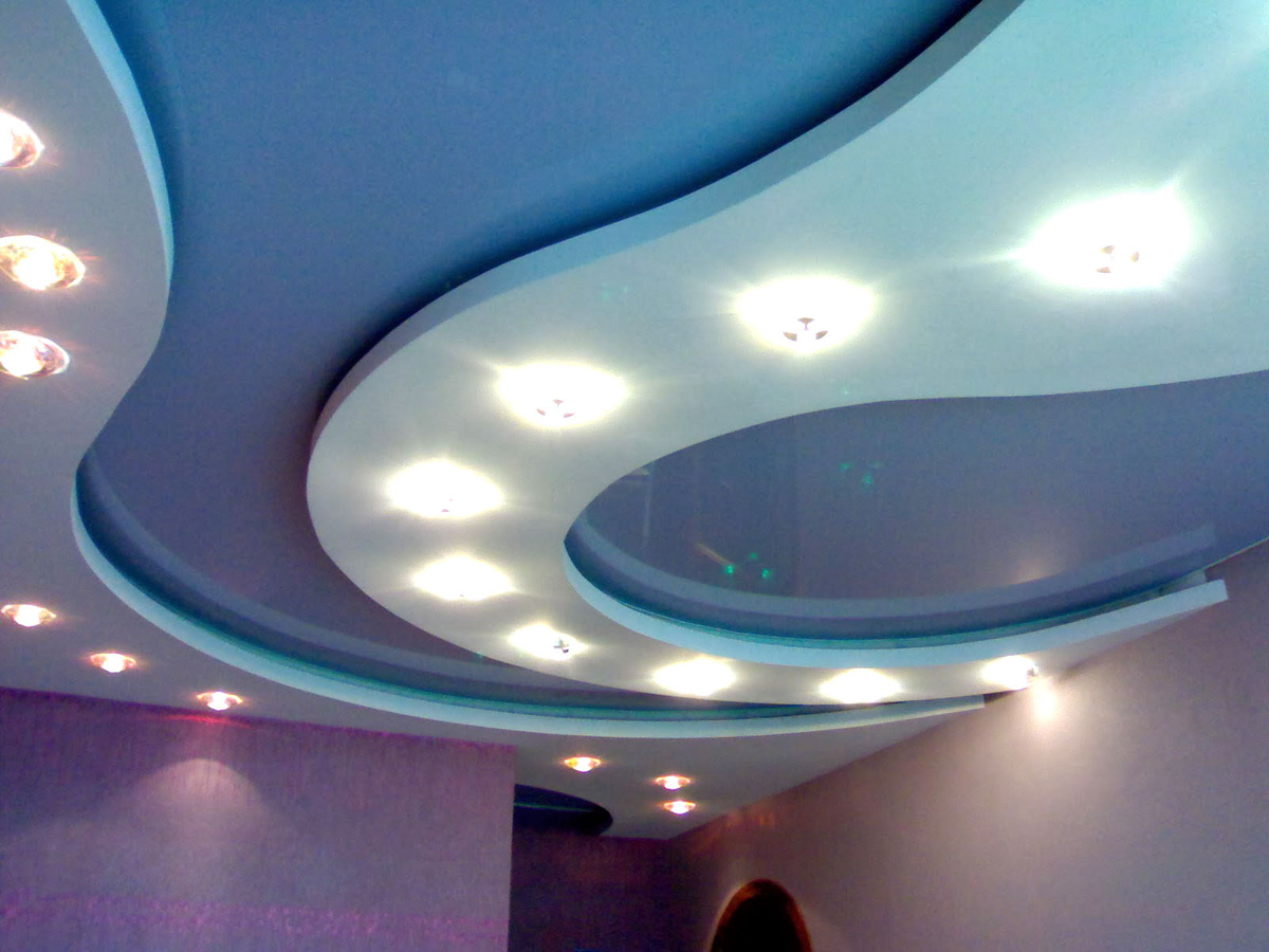 Самыми доступными и практичными остаются полотна ПВХ. Они легко поддаются гигиенической обработке, поэтому часто монтируются во влажных помещениях, на кухне, в офисе. Несмотря на распространенное мнение, что такой вид отделки ограничивает интерьерные возможности, проблема установки мебели на вертикальных распорках решается с помощью отверстий, по специальной технологии выполненных в пластиковом полотне.
