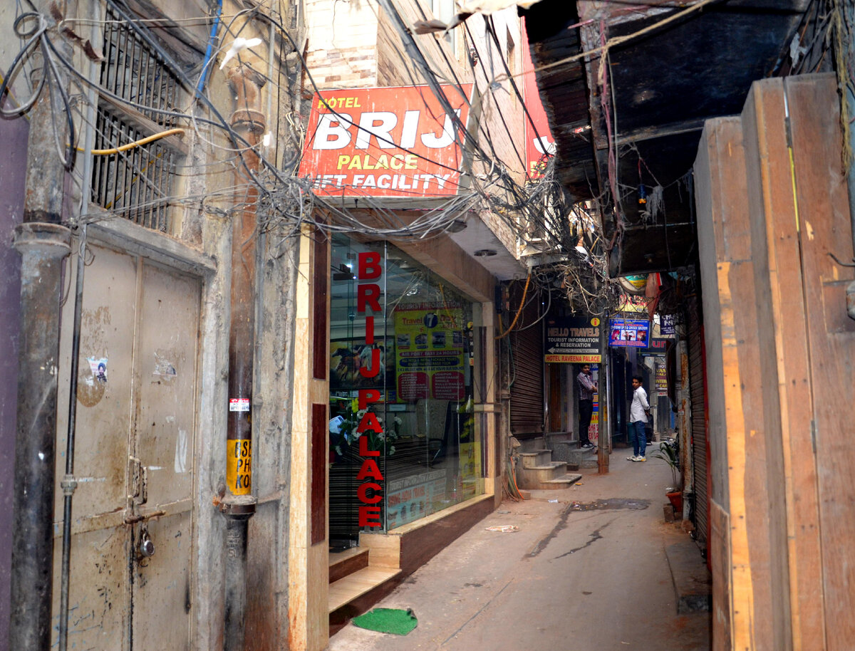 Вход в наш отель в Дели на улице Мейн Базар. Нет, не эта грязная дверь с замком. А вон та, стеклянная, на которой написано BRIJ PALACE. А вот и канализационная труба, как раз около грязной двери. Фото автора.