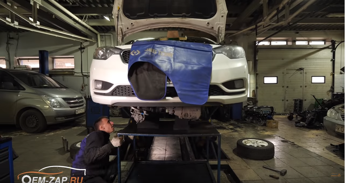 На фото процесс снятия двигателя с автомобиля. Автомобиль на подъемнике.