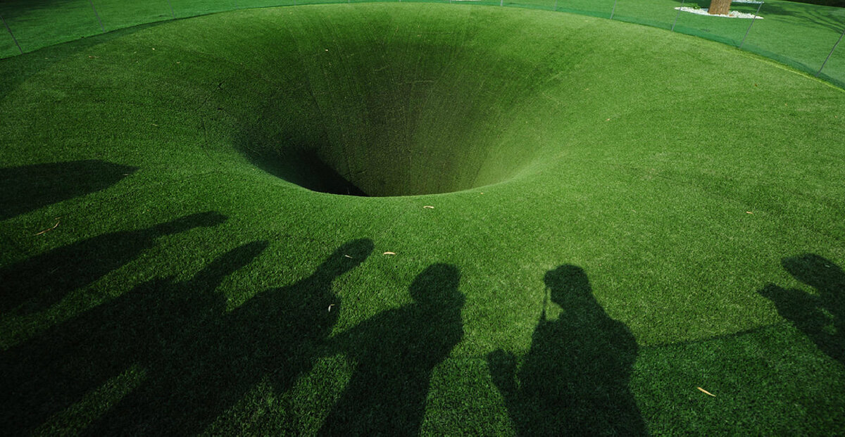 Глубокая воронка. Зеленая дыра. Яма в земле. Огромная воронка. Огромная дыра в земле.