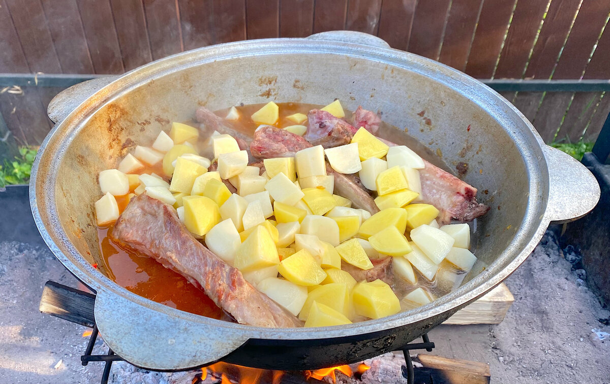 Ребрышки с овощами в казане на костре. Картошка с ребрышками в казане на костре. Блюда на мангале в казане на костре. Блюда на мангале. Готовить еду в казане на костре.