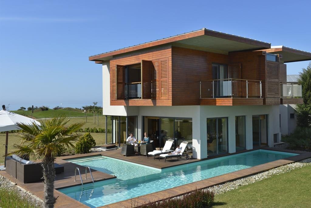 Скажу наперед, от пребывания на вилле, мы остались в восторге. Нам предоставили двухэтажное здание со своей территорией и тремя бассейнами (маленький внутри и два на улице, один глубиной 40 см, другой 140 см). 
В здании находится три спальных комнаты, в каждой имеется гардероб и санузел. Всего имеется 4 туалета и три душа. При одной комнате есть ванная и две раковины. Отдельный просторный зал. Также имеются сауна, балконы (два широких и один маленький) с видами на территорию виллы. Окна панорамные. Возле бассейна большой стол со стульями и диваном, есть 4 лежака и зонтик.

Из техники на вилле имеются три телевизора (один в общем зале с USB входом и по одному в двух спальнях), большой холодильник (ежедневно пополнялся пепси, мириндой и простой водой), микроволновка, два фена, вайфай роутер (работает отлично), кондиционер общий, регулируется в каждой комнате.

Из душевых принадлежностей были гели, шампуни, мочалки, пена для бритья, ватные палочки, лосьоны. Были халаты и тапочки.

За 14 ночей пребывания не убирались только один день, полотенца и постельное бельё меняли практически каждый день. Иногда забывали доложить туалетную бумагу.
По питанию отдельная история. Мне и моей жене все очень понравилось, было несколько видов мяса (курица, индейка, телятина или баранина), рыба (разные виды), все в разных вариациях, тушеное, постное, жареное. Каждый день предлагались по два вида супа, часто острые. Также было множество овощей и фруктов (вероятно, с соседних парников), были бананы, груши, яблоки, виноград, апельсины, мандарины и т.д. Был отдельный уголок с питанием для детей. Нашим родственникам питание не очень понравилось, сказали, что быстро приедается. 
Также давали мороженое из козьего молока (4 вкуса) в обеденное время в буфете и на ужин в основной столовой, очень вкусно.

Была открытая столовая ближе к морю, где давали шаурму, бурито, бургеры, треугольники с сыром, картошку фри, овощи, фрукты, айран, пироженки. Там же находился бар, где можно было взять различные напитки (соки, воду, чай, кофе, пиво Туборг, разные коктейли). Всего в отеле 4 основных бара, один круглосуточный возле лобби. Есть кальяны (20-25 $). Рядом с пляжем делали вкусную пиццу/лепешки. Так же есть рестораны а-ля карт, но мы не ходили.

В отеле имеются различные активности (дискотеки, игры, фитнес тренировки, классный аквапарк). Анимация активная.