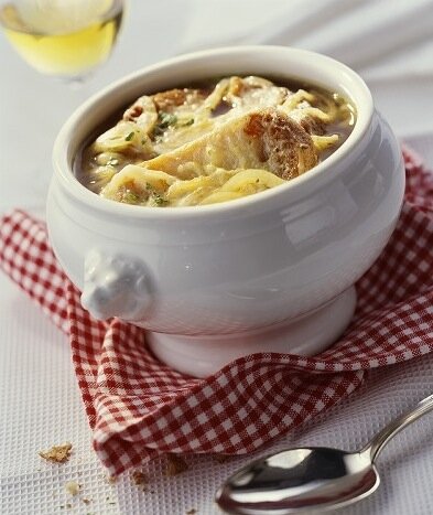 автор статьи, конечно, приврал. Припасы там были, ну а теперь подробнее...

То ли охота не дала трофеев, то ли интендантство плохо сработало, но из всех продуктов слуги смогли принести Людовику XV лишь несколько луковиц, кусок сливочного масла и бутылку то ли шампанского, то ли белого вина. Озадаченный и проголодавшийся король выпил вино, озверел, убил слуг, пожарил их и съел  обжарил порезанный лук в масле, долго помешивая его, и в конце залил вином и поварил некоторое время. Получилось вкусно (это я гарантирую) . Некоторые утверждают, что эта история произошла не с ним, а с его прадедом, Людовиком XIV. Вынужденный рецепт одного из Людовиков, конечно, помог луковому супу проникнуть в королевский дворец, хотя их подданым луковая похлёбка была известна давно.


"Людовик XV, король Франции. Жан Батист ван Лоо, XVIII век" 

Есть ещё одна правдоподобная версия, тоже связанная с Людовиком XV. Николя Аппер, чьё изобретение консервирования пищевых продуктов обеспечило провиантом наполеоновские кампании, был замечательным поваром, и в частности, проявлял свои кулинарные таланты в особняке "Золоое яблоко" в родном Шалон-ан-Шампань . Там регулярно останавливался экс-король Польши Станислав Лещинский, когда отправлялся в Версаль, чтобы навестить свою дочь Марию, супругу Людовика XV. Как-то раз ему подали луковый суп, приготовленный Николя Аппером. Вкус настолько поразил бывшего монарха, что ночью он не мог уснуть и успокоился только когда уничтожил все луковые закрома  спустился на кухню в халате и потребовал, чтобы повара приготовили суп при нём, комментируя свои действия. После этого случая Аппер назвал своё произведение "луковый суп Станислава" и опубликовал рецепт в книге, изданной в 1831 году.

Так или иначе, луковый суп стал, пожалуй, самым классическим блюдом французского меню. Еу отдавали должное и грузчики Чрева Парижа, которые ели суп на завтрак после тяжёлой рабочей ночи, и буржуа, которые гордились умением его готовить, и повара дворянских и королевских фамилий. Александр Дюма в своём "Большом кулинарном словаре" приводит аж с десяток рецептов приготовления лукового супа. Иногда французы называют его супом пьяниц и начинают им свои "опохмел-parties". С этим соглашался Эрнест Хеменгуэй, считавший луковый суп прекрасным завтраком для тех, кто "не спал".

И в наше время луковый суп объединяет абсолютно разных по социальному статусу людей. Вот как иллюстрирует это Жак Пепен, бывший когда-то личным поваром генерала де Голля. Он любил отправиться после работы в Ле-Аль, квартал, построенный на месте снесённого Чрева Парижа, но сохранивший вековые традиции этого рынка. "Оживление и суета на улицах и в кафе начинались часов с 3 утра и успокаивались часам к 7-8. В "Свиной ножке" [Pied de cochon - один из известнейших парижских ресторанов] ... здоровые и голосистые мясники в заляпанных кровью фартуках соседствовали с элегантными парижанами во фраках и парижанками в вечерних платьях, зашедшими распить бутылочку шампанского или поужинать после спектакля..." Ресторан был знаком на весь Париж своим луковым супом - gratinée à l'oignon, и в течение ночи его посетители съедали сотни порций, подаваемых индивидуально в супнице под названием "голова льва" - tête de lion.



Важно и то, что луковый суп наиболее историчен из современных супов. Изначально супом вообще назывался сухой ломоть хлеба, который заливали мясным или овощным отваром. Так что крутоны в луковом супе - дань давней традиции.

Классический рецепт можно видоизменять. Можно обойтись без вина, а можно наоборот заменить белое вино красным - цвет супа будет более тёмным и насыщенным (/лично я бы в таком случае заменил бы ещё и белый лук красным/ - прим.P@$Ik). Бульон может быть и телячьим, и говяжьим, и даже утиным. Вегитарианцы могут готовить луковый суп на овощном бульоне или даже на воде (/но лично я против экспериментов в таком ключе/ - прим.P@$Ik).