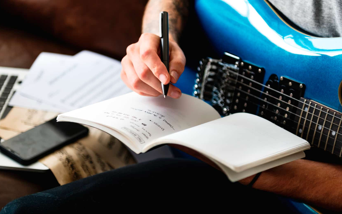 парень с гитарой. человек сочиняющий музыку. Songwriting фото. человек пишет музыку. увлечение музыкой.