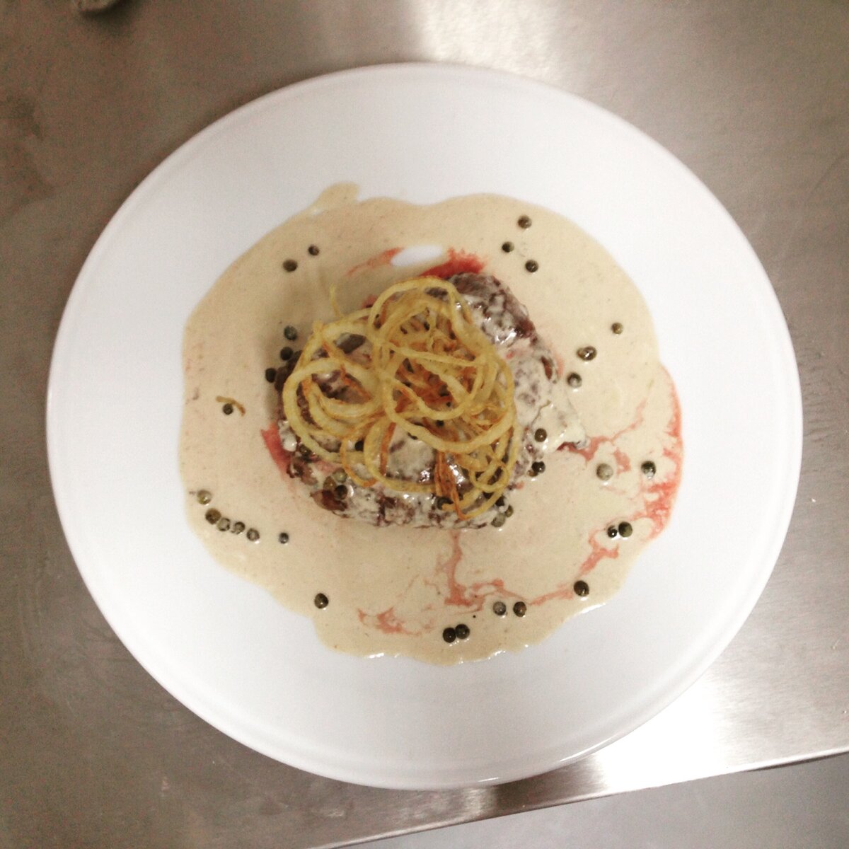 Стейк в сливочном соусе, декорированный луковыми кольцами. 