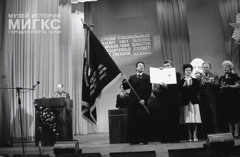 Негатив черно-белый «Первый секретарь Сочинского ГК КПСС, депутат Верховного Совета РСФСР В.Ф. Гавриленко держит знамя города, к которому прикреплен орден Отечественной войны I степени». Фотограф: Э.Л. Боровский. СССР, г. Сочи, 1982 г.