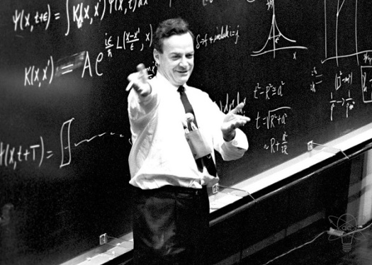 Ричард Фейнман на лекции. На доске, помимо формул, видны также графические объяснения материала.