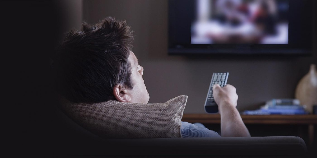 Громко смотрит телевизор. Перед телевизором. Человек на диване перед телевизором. Человек телевизор. Человек сидит перед телевизором.