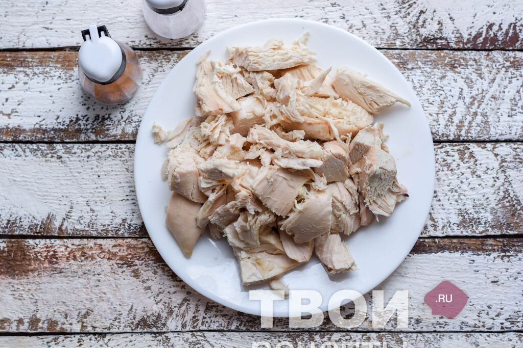 1 - Куриную грудку сполоснуть и насухо обтереть бумажными салфетками. Переложить мясо в кастрюлю, влить нужное количество воды, добавить немного специй для усиления вкуса – лавр, душистый перец, гвоздику, паприку. Также можно добавить цельный сегмент сельдерея, морковь и луковицу. В итоге получится просто отменный бульон. Варить куриное мясо до готовности – около часа. Дать грудке остыть прямо в бульоне, это будет залогом того, что мясо получится сочным, а не сухим. После грудку отделить от костей, чистое филе нарезать произвольно. 