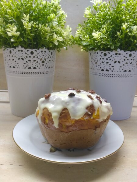 Готовый кулич, покрытый белой глазурью и украшенный изюмом