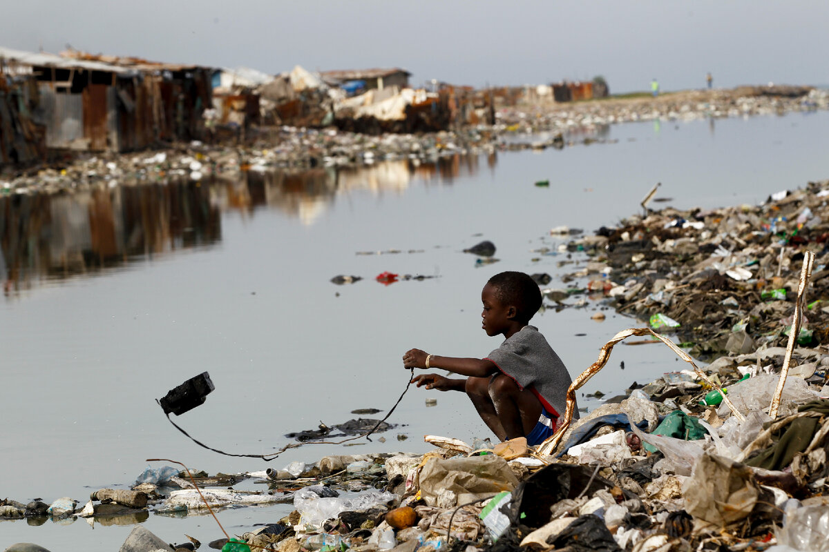 Мальчик играет на берегу канала в Порт-О-Пренсе