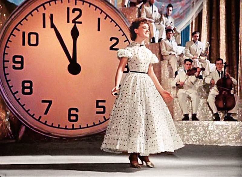 Есть вещи, без которых в нашей стране невозможно представить себе новогодние праздники. Например, елка, салат "Оливье", мандарины. И, конечно, знаменитые комедии Эльдара Рязанова - "Карнавальная ночь" и "Ирония судьбы". Причем, к съемкам "Карнавальной ночи" Рязанов приступил по воле случая, в то время он даже не предполагал, что его комедии будут так популярны в Советском Союзе. В пятидесятых годах молодой выпускник ВГИКа Эльдар Рязанов мечтал о карьере режиссера-документалиста, на экраны один за другим выходят его фильмы: "Они учатся в Москве", "Дорога имени Октября", "На первенство мира по шахматам". Темы, нужно сказать, далекие от комедийного жанра. Но, в 1956 году директор "Мосфильма" Иван Пырьев предложил ему экранизировать сценарий Владимира Полякова и Бориса Ласкина. Сам сценарий уже несколько лет пылился на полках, никто из режиссеров не горел желанием браться за съемки этой комедии, считая бесперспективной. И Рязанов не пришел в восторг от такого предложения, у него были совсем другие планы, работа над драматическим фильмом "Встречи на Камчатке". Но Пырьев был настойчив, и Рязанову пришлось, без особого восторга, приступить к съемкам. Как окажется, именно благодаря комедии "Карнавальная ночь" Рязанов будет известен всей стране. А начал свою работу Рязанов с того, что серьезно переработал сценарий. Затем начался подбор актеров на роли. Режиссеру-дебютанту пришлось работах с известными мастерами кино. Например, на роль директора Дома культуры Огурцова был приглашен Игорь Ильинский, хотя сам Рязанов планировал отдать эту роль театральному актеру Петру Константинову. Пырьев в этом вопросе был непреклонен - бюрократа Огурцова будет играть только Ильинский. К съемкам Игорь Владимирович Ильинский относился очень серьезно. в одном из эпизодов ему пришлось доставать из кармана живых голубей вместо доклада. Этот трюк Ильинский отрабатывал под руководством иллюзиониста Игоря Кио. несмотря на зрелый возраст, Ильинский старался самостоятельно выполнять все трюки, даже самые опасные. Людмила Гурченко в комедии "Карнавальная ночь" также появилась благодаря Пырьеву. Пока Рязанов искал актрису на роль Леночки Крыловой, Пырьев уже утвердил кандидатуру Гурченко. Но со своей ролью молодая актриса справилась замечательно, картина стала популярной во многом благодаря таланту 21-летней Гурченко. Даже несмотря на то, что это была лишь вторая ее работа в кино, чуть раньше Людмила снялась в картине Яна Фрида "Дорога правды". одним из самых колоритных актеров комедии "Карнавальная ночь" стал, без сомнения Сергей Филиппов в роли лектора Некадилова. Его знаменитая фраза: "Есть ли жизнь на Марсе?" быстро стала крылатой. За всю свою продолжительную актерскую карьеру Филиппову почти не доводилось играть главных ролей, но любое его появление на экране, даже в эпизоде, становилось для зрителей настоящим праздником. Несколько лет назад Юрий Филиппов, сын актера, в соавторстве с Татьяной Гринвич, написал книгу о своем отце. А называлась она "Есть ли жизнь на Марсе..." Съемки новогодней комедии проходили летом 1956 году в театре Советской Армии. В это время труппа была на гастролях, здание было свободно, поэтому, большая часть фильма была отснята именно здесь. Работу над комедией "Карнавальная ночь" провели в рекордные сроки, всего за пять месяцев. Худсовет, едва просмотрев первые отнятые отрывки, решил, что успехом фильм пользоваться не будет, он слишком скучный и наивный. Но, съемки решили не прекращать, молодому Рязанову разрешили довести работу до конца. А сам Эльдар Александрович, даже через много лет после съемок, говорил, что картина стала популярной благодаря актуальной теме. "Огурцовы", которые "безапелляционно и безграмотно пытаются руководить", были и будут всегда. Никакой особой рекламы фильма перед выходом на экраны не было. Премьера состоялась в самом конце 1956 года - 28 декабря. А вскоре зрители уже штурмовали кассы, чтобы купить билет на этот фильм. За 1957 год картину посмотрели около 50 миллионов зрителей. А Игорь Владимирович Ильинский сказал Людмиле Гурченко: "После этой картины ты будешь очень популярной. Готовься…». Через некоторое время после премьеры на имя Людмилы Гурченко пришло необычное письмо из Африки. Принц одной из стран Черного континента предлагал молодой актрисе руку и сердце. Прошло 50 лет после выхода картины, и режиссер Рязанов снял фильм «Карнавальная ночь — 2, или 50 лет спустя». Этот фильм также снимался очень быстро, с сентября по декабрь 2006 года. Вместо Огурцова в Доме культуры новый директор - Кабачков. А вместо Леночки Крыловой в ДК работает другая девушка - Алена Крылатова. Несмотря на то, что премьера фильма подогревалась мощной рекламой, стать таким же популярным ремейк не смог. Как видно, дважды в одну реку войти нельзя 
Источник: https://i-fakt.ru