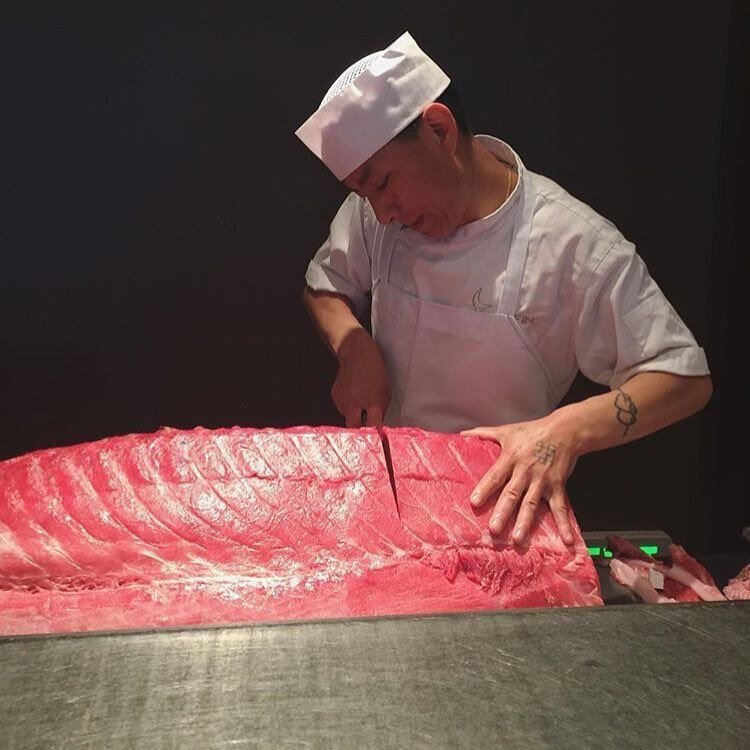 Японский сотрудник рыбного рынка Цукидзи разделывает тушку тунца