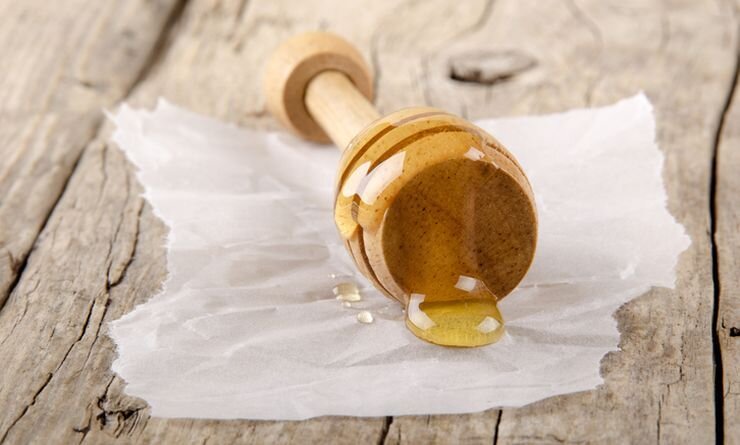 Натуральный мед лежит на поверхности бумаги.