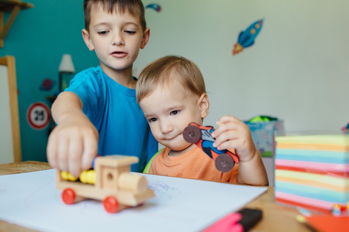 His brother play with toys. Братья играют вместе. Стол с ребенком играет в машинки. Младенец играет с приложением. Ребенок играет сам с собой.