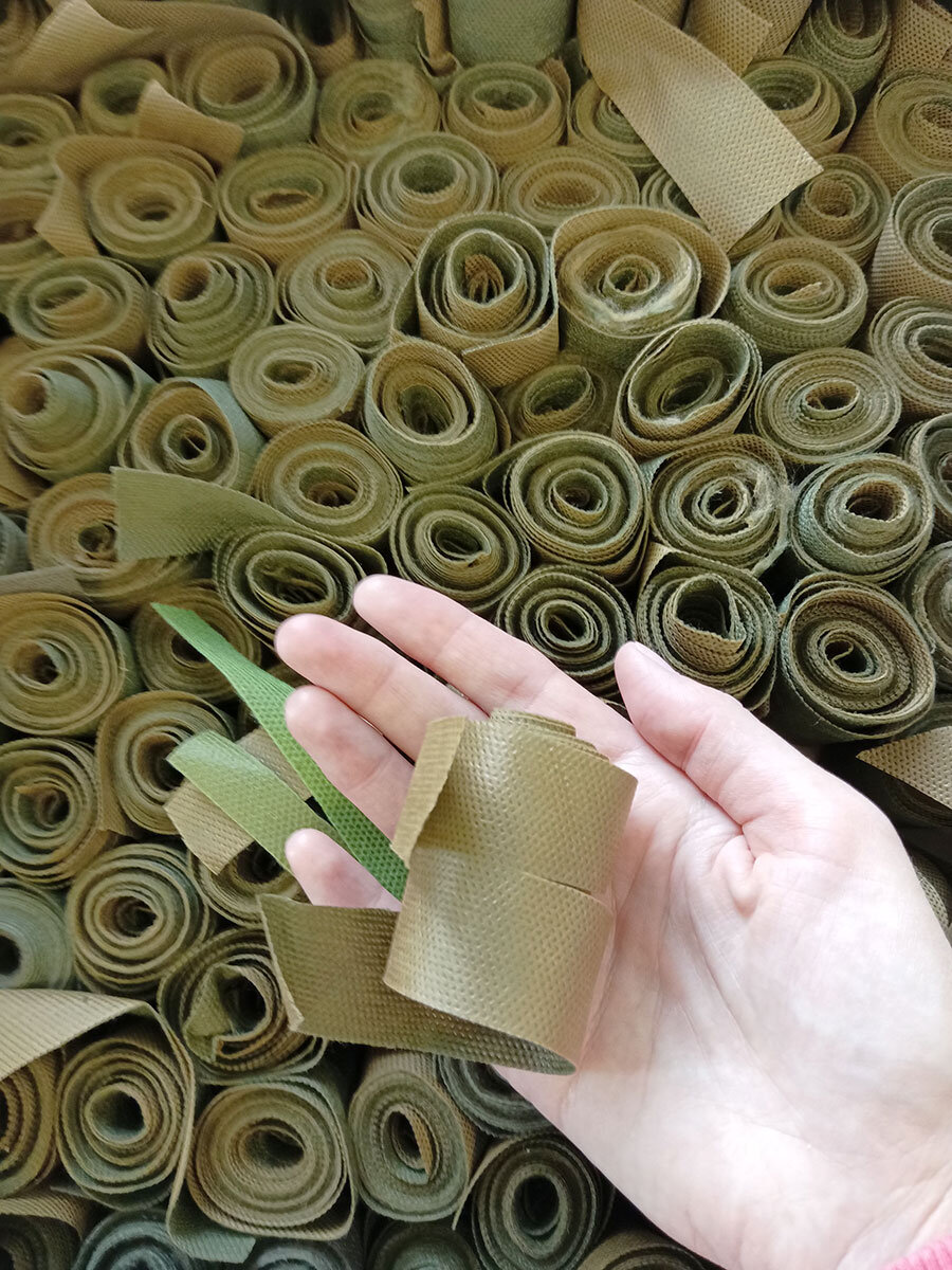 88-летняя Юлия Федоровна Ашмульцкая скручивает нарезанные ленты в рулончики, чтобы мастерам было легче и быстрее плести