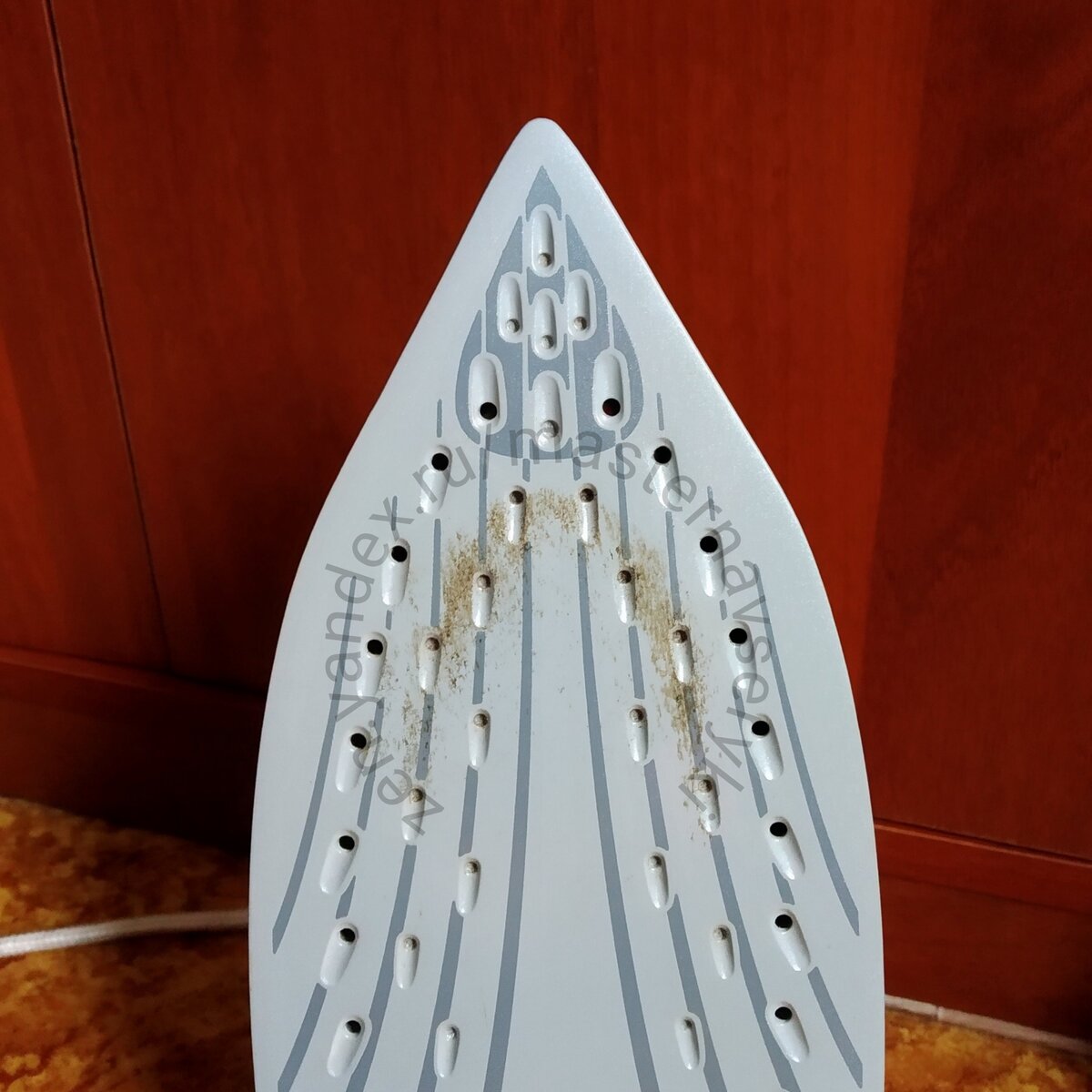 Пригоревшие волокна ткани на керамической подошве утюга.