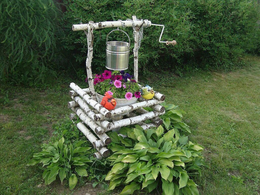 Интересный колодец-клумба из брёвнышек.