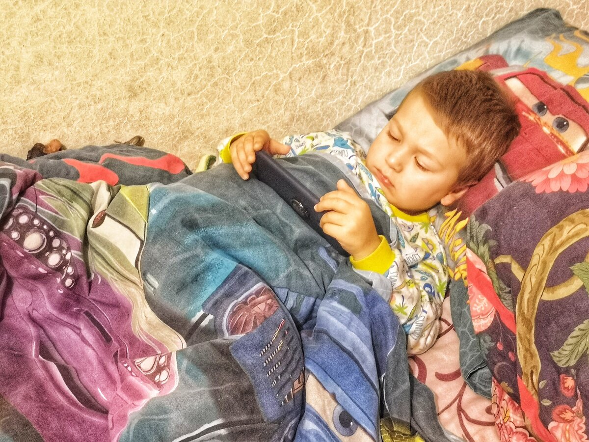 Смотрит мультики в кроватке