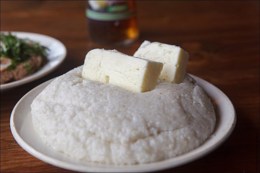 🥧 Мамалыга - главное блюдо абхазской кухни. Это каша из крупно помолотой кукурузной муки, которую едят несколько раз в день. Раньше её делали из просо, но потом полностью перешли на кукурузу - мамалыгу из просо вы сейчас вряд ли найдете. Возможны вариации мамалыги: иногда ее заправляют кисломолочным сыром (айладж), иногда варят на молоке с сыром (ачамыква), из кукурузной муки делают пресные лепешки (амгял) или своеобразную халву (ацвырцма).

🧀 Мамалыгу, как правило, "нашпиговывают" сулугуни, который там тает и заодно немного солит ее (изначально мамалыга пресная и никогда соль в неё не добавляется). Также её часто поливают вареной фасолью или просто ткемали - подливкой из зеленой алычи. Кстати, ткемали - самый популярный и невероятно вкусный соус, не спроста его заготавливают банками.

🌽 Традиционная кухня абхазов складывалась под влиянием местных особенностей ведения хозяйства, природных и экономических условий. Основу рациона абхазов издревле составляли кукуруза, просо и молочные продукты, в прошлом рацион значительно пополняли дичь и съедобные дикорастущие растения.

🍖 Мясо в традиционной абхазской кухне варят большими кусками или жарят. Особенно популярно мясо животных или птиц, жареное на вертеле. Бульон, как правило, не используется, и супы не готовят. Рыба тоже практически отсутствует.

🥦 Очень распространены овощные блюда (зеленая фасоль, капуста, свекла, сассапариль) с грецким орехом. Такой своеобразный салат называется ачапа. Основное овощное блюдо, чаще всего подаваемое вместе с мамалыгой, готовят из зерен фасоли со специями (акуд). К столу обязательно подают овощи: летом – свежие, зимой – соленые. 

🌿 Почетное место на столе всегда занимает зелень: петрушка, укроп, киндза, цицмат.

🌶 Ну и конечно же, нельзя не сказать про аджику! Самой известной приправой традиционной абхазской кухни является именно она, этот «бренд» хорошо известен в России и в мире. Ароматная, острая пастообразная приправа добавляется практически во все блюда. Основной ингредиент аджики - красный перец, а также чеснок и сухие пряные травы. Аджика улучшает усвояемость пищи и пищеварение.