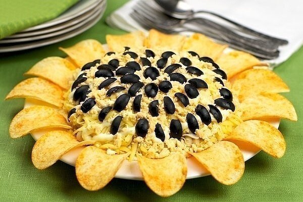 Нам понадобится: • 300 грамм куриного филе;
• Чипсы;
• 6 куриных яиц;
• Подсолнечное масло;
• Майонез;
• Репчатый лук;
• Маслины;
• Грецкие орехи;
• 150 грамм сыра;
• 250 грамм свежих грибов;

Способ приготовления:

• Шаг первый. Варим до полной готовности куриное филе в кастрюле с водой. Мелко нарезаем его.

• Шаг второй. Теперь отвариваем вкрутую куриные яйца, чистим их и натираем на мелкой терке по отдельности желтки с белками.

• Шаг третий. Чистим репчатый лук, нарезаем его мелко вместе с грибами, обжариваем на подсолнечном масле в сковородке.

• Шаг четвертый. Затем измельчаем грецкие орехи, сыр натираем на мелкой терке. После этого выкладываем в салатницу слоями подготовленные ингредиенты.

• Шаг пятый. Сначала кладем куриное филе, майонез, жареные грибы с луком, а затем ложем грецкие орехи + майонез, яичные белки + майонез, тертый сыр + майонез и яичный желток.

• Шаг шестой. После всего этого украшаем салат сверху половинками маслин, зеленью, а по бокам выкладываем чипсы. Приятного аппетита!