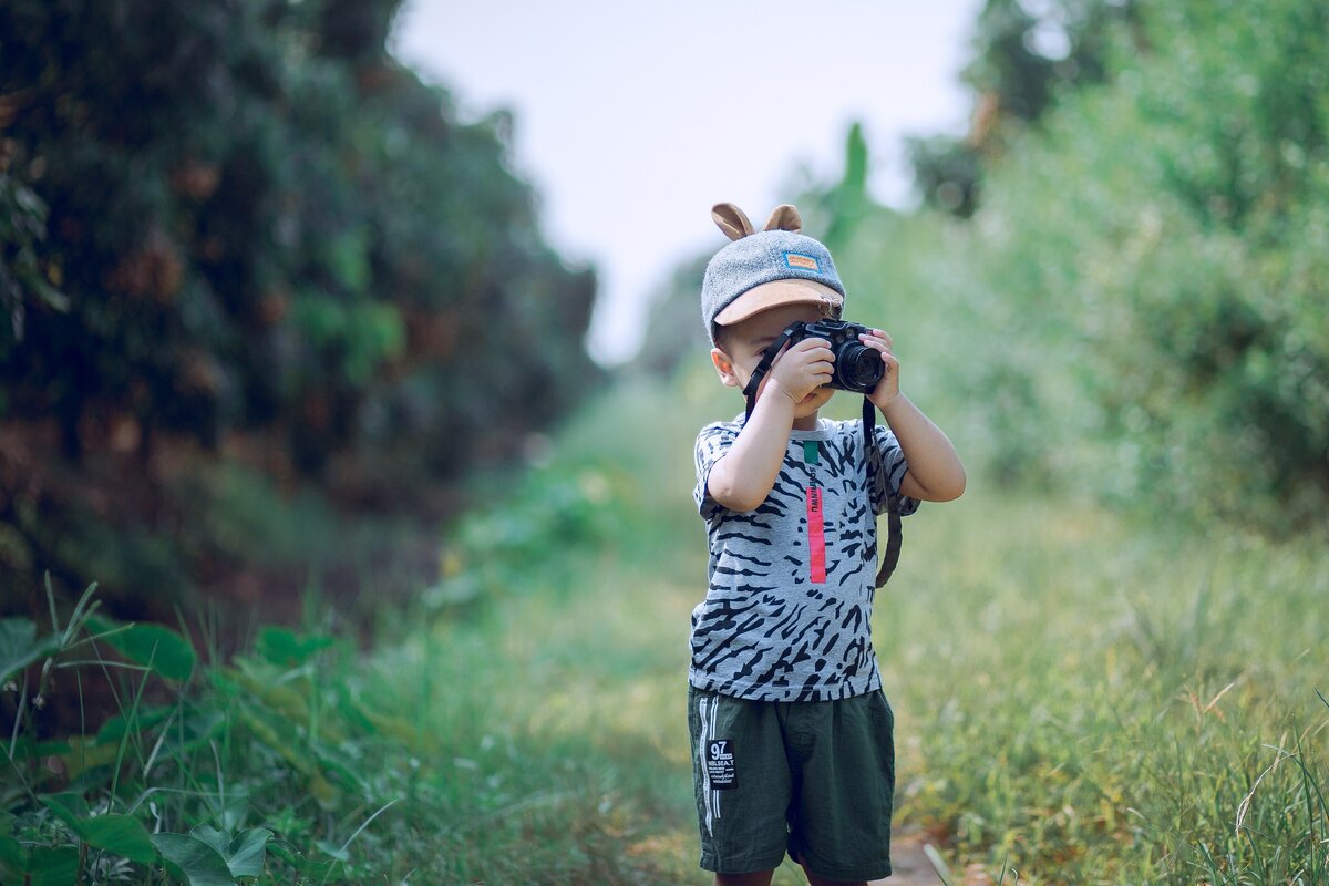 https://www.pexels.com/photo/boy-using-camera-near-green-leaf-plants-1374510/