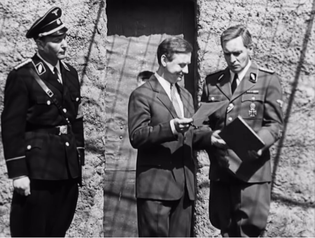 Шелленберг с улыбкой подписывает акт о расстреле троих своих личных адъютантов по особым поручениям, он доволен, что их убили быстро