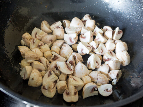 Шампиньоны нарезаем на 2-4 части в зависимости от размера. Мелко рубим имбирь и чеснок .В вок кладем грибы и жарим, помешивая, 3-4 минуты. 
