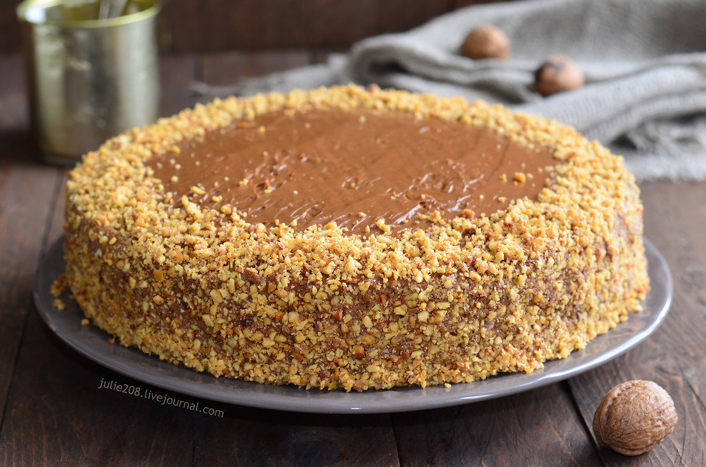 Если в тесто добавлять сметану, то оно становится в разы нежнее. Для данного тортика крем готовится с добавлением сгущенки и масла. А вот сахара в рецепте нет, ведь и так торт получается очень сладким. 
Потребуется:

- два стакана муки;
- по 250 г сметаны, сгущенки;
- три яйца;
- две ложки какао;
- щепотка соды.
Крем: по 200 г сгущенки, масла (берут качественное сливочное);
- орехи.

Приготовление:

1. Сначала сметану смешивают с яйцами – должна получиться однородная масса. Добавляют сгущенку, муку, щепотку соды. Снова все смешивают, далее делят тесто на две равные части. Одну оставляют неизменной, во вторую добавляют какао.
2. Выпекают два коржа при 200 градусах (достаточно двадцати минут. остужают прямо в форме. Потом вытаскивают, каждый разрезают пополам вдоль – получится по два коржа светлого и темного цвета.
3. Теперь самое вкусное – готовка крема. Масло взбивают со сгущенкой. Получится пышная и устойчивая консистенция, так что сбивать лучше дольше. Подготовленные коржи промазывают кремом, соединяют (нужно чередовать по цветам). Кремом промазывают верхушку и боковины.

Остается перед подачей посыпать торт сверху рубленными орехами. Можно взять любые любимые орешки на усмотрение. очень красиво смотрятся хлопья миндаля.