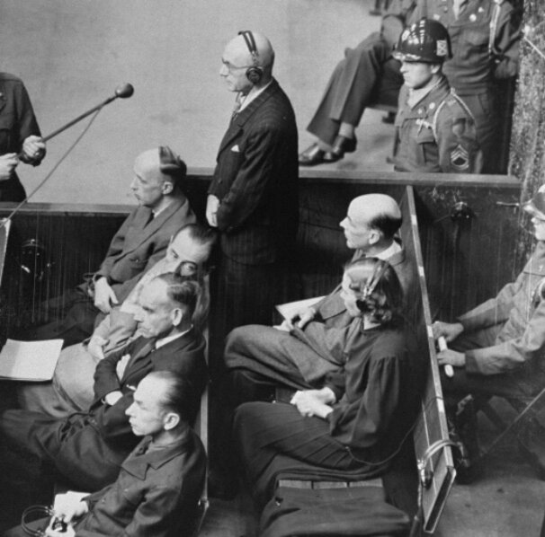 Начальник Главного управления здравоохранения «Лебенсборн» Грегор Эбнер на заседании суда во время Нюрнбергского процесса по делу о расовых преступлениях. (Стоит в наушниках перед микрофоном).