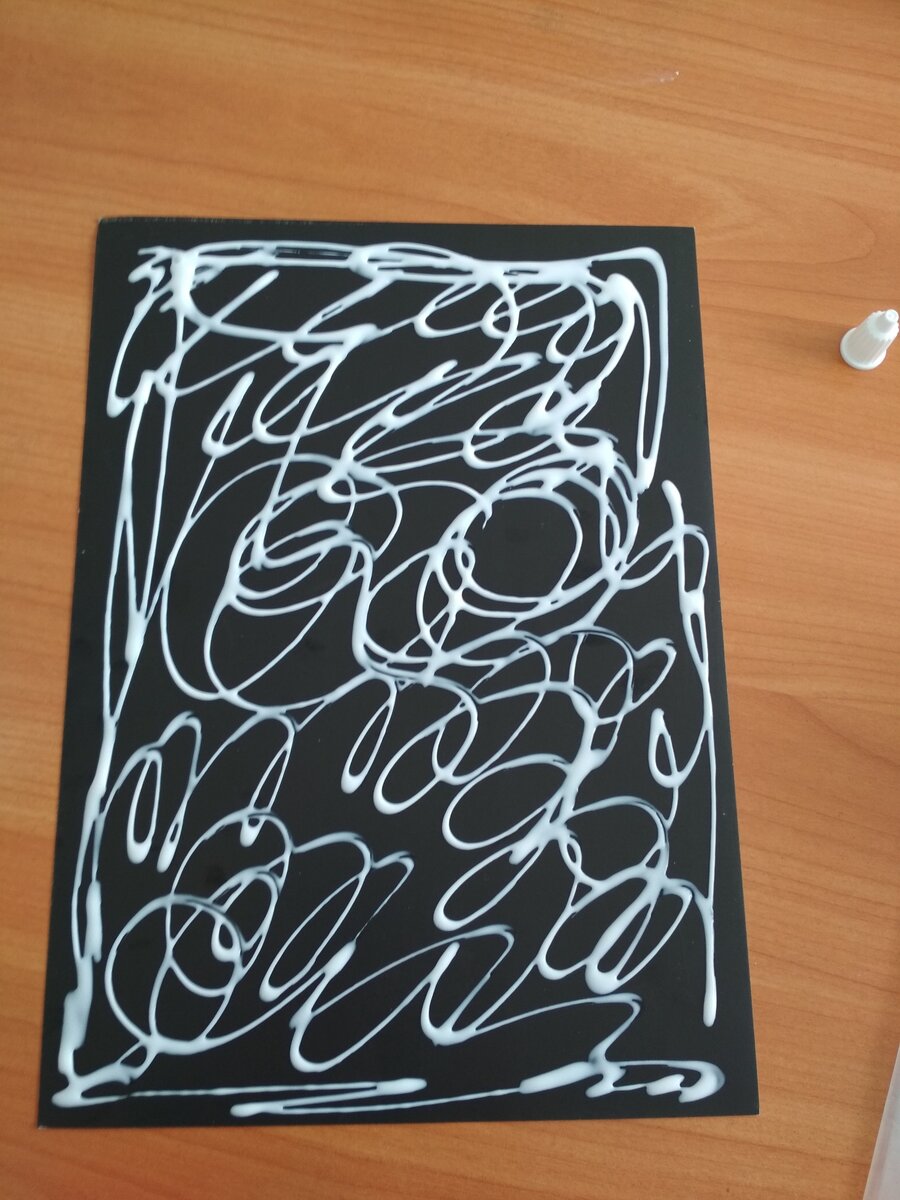 Берём картон черного или синего цвета. Наносим клей ПВА на весь формат (А4).