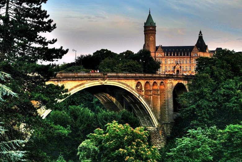 Люксембург Официально данное государство называется Великим Герцогством Люксембург. Размещается оно в западной части Европы. В топ-10 самых богатых стран мира герцогство попало за счет того, что данная территория является оффшорной зоной, а это характеризуется большими инвестиционными вложениями в экономику Люксембурга. Мост Адольфа в Люксембурге. Это крупнейший финансово-туристический центр Европы, который приветствует регистрирование международных транснациональных организаций и компаний. Напомним, что оффшорная зона предполагает осуществление деятельности без уплаты налоговых платежей, именно поэтому в Люксембурге зарегистрировано больше двух сотен банковских учреждений и более тысячи инвестиционных фондов. Основная часть ВВП формируется из доходов от сферы услуг, финансов и торговли. В герцогстве хорошо развиты такие виды промышленности: металлургическая; сталелитейная; химическая; фаянсовая; цементная; деревообрабатывающая. Благодаря развитию отрасли добычи чугуна и железа Люксембург стал одним из крупных экспортеров данных видов металла. Большая часть доходов от экспорта формирует ВВП, который равняется 104 003 USD. Источник: https://visasam.ru/emigration/vybor/bogatye-strany-mira.html