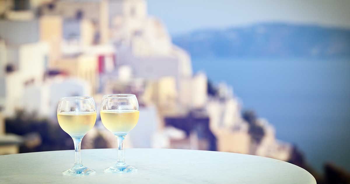 Бокалы белого вина на фоне острова "Санторини"